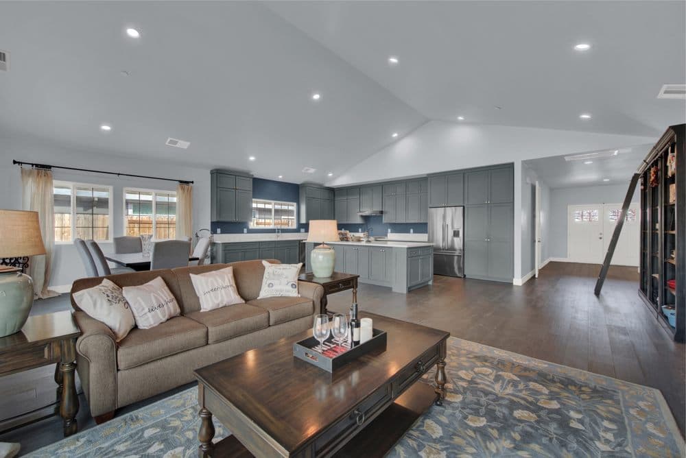 Open concept living room with gray and blue kitchen in Sacramento — Keystone Building Services